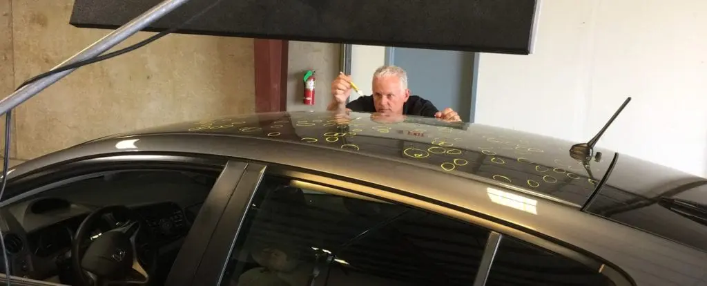 Specialist doing paintless dent repair on car at Auto Hail Zone in Colorado Springs