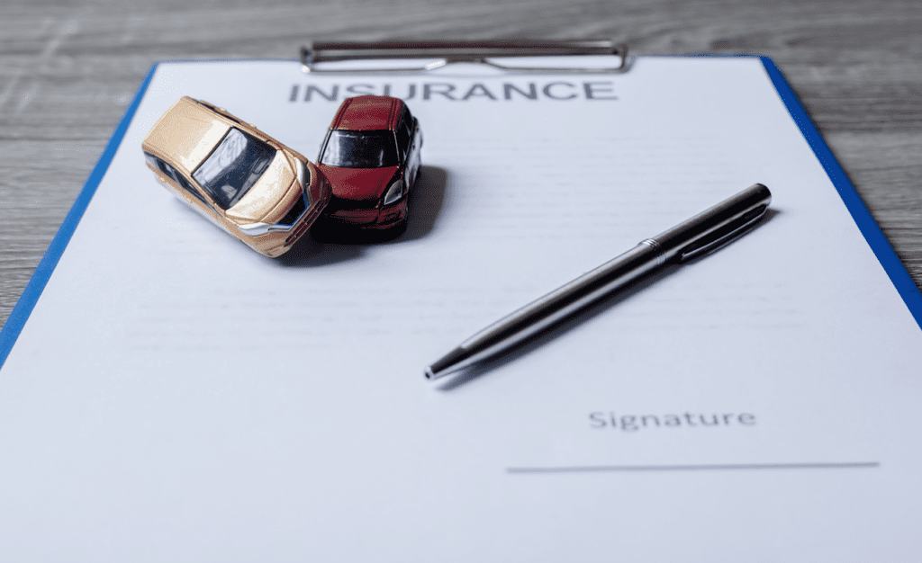 two toy cars sitting on a car insurance contract